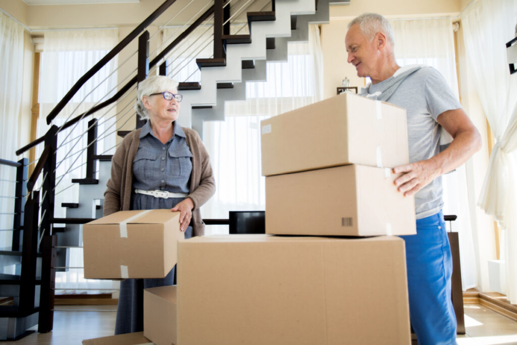 A couple stacking cardboard boxes in their home as they prepare for a move.
